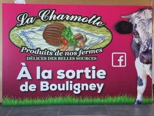Panneau publicitaire "La Charmotte" à Boulingen, avec un logo et une vache.